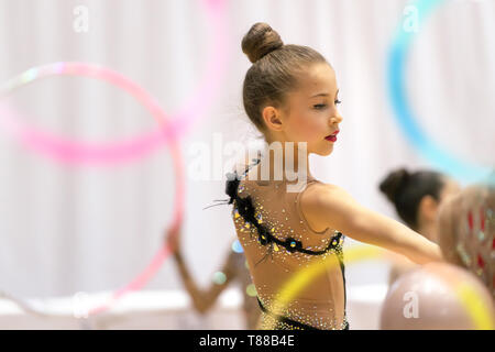Nice little gymnast girl performing a dance with a hoop, healthy active childhood, playing sports, taking part in a rhythmic gymnastics competition Stock Photo
