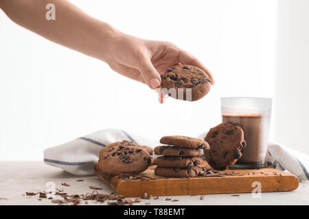 Woman taking chocolate cookie from wooden board Stock Photo