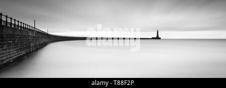 Winter clouds providing ideal conditions for a panoramic long exposure B&W of Roker Pier with some soft reflections in the North Sea. Stock Photo