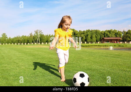 Cute little girl playing football in park on sunny day Stock Photo