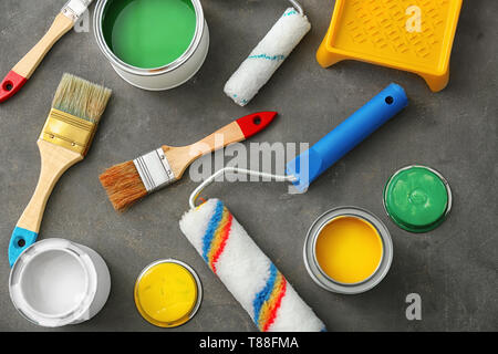 Cans of paint, roller and brushes on grey background Stock Photo