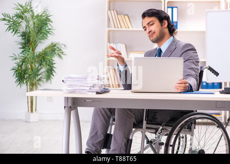 Young handsome employee in wheelchair at the office Stock Photo