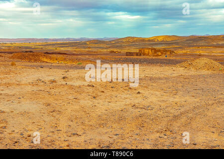 Black abandoned desert in Merzouga Sahara near Erg Chebbi, on the background of a sand dune and an old village, Morocco in Africa Stock Photo