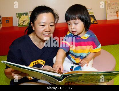 Beijing, China. 12th May, 2019. A girl reads a book with her mother in Beijing, capital of China, May 12, 2019. An early childhood education center held a picture book reading event to promote parent-child reading in Beijing. Credit: Liu Lianfen/Xinhua/Alamy Live News Stock Photo