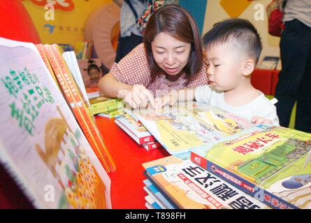 Beijing, China. 12th May, 2019. A boy reads a book with his mother in Beijing, capital of China, May 12, 2019. An early childhood education center held a picture book reading event to promote parent-child reading in Beijing. Credit: Liu Lianfen/Xinhua/Alamy Live News Stock Photo