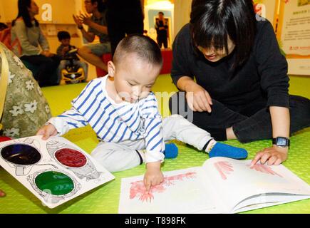 Beijing, China. 12th May, 2019. A boy reads a book with his mother in Beijing, capital of China, May 12, 2019. An early childhood education center held a picture book reading event to promote parent-child reading in Beijing. Credit: Liu Lianfen/Xinhua/Alamy Live News Stock Photo