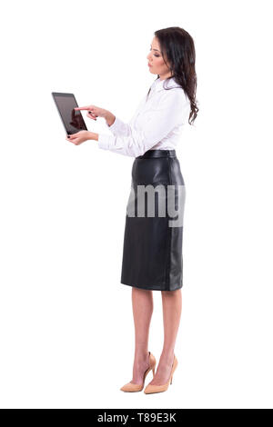 Side view of elegant young business woman using interactive tablet touch screen. Full body isolated on white background. Stock Photo