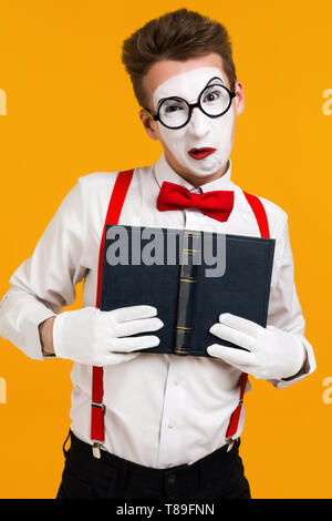 portrait of mime man artist with book ape isolated on yellow background Stock Photo