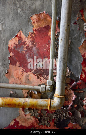 Paint peeling off plastered wall with two piped Stock Photo