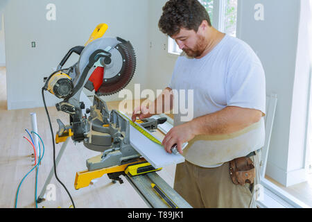 Building contractor worker using measuring and marking a before cutting wooden trim board Stock Photo