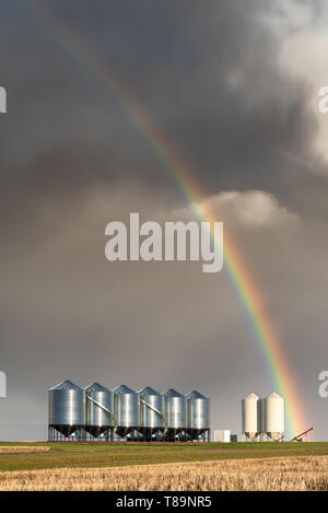 Rainbow over grain bins during spring storm on the prairies in Saskatchewan Stock Photo
