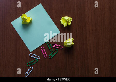 Upper view three small paper balls colored clips stick pad wooden table Design business concept Empty template copy space text for Ad website isolated Stock Photo