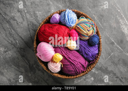 Wicker bowl with colorful knitting yarn on table Stock Photo