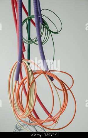 A detail view of colorful electrical cables hanging from the ceiling in spirals and bundles on a construction site Stock Photo