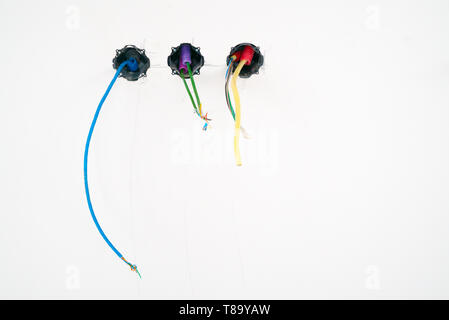 A detail view of colorful electrical cables hanging from the ceiling in spirals and bundles on a construction site Stock Photo