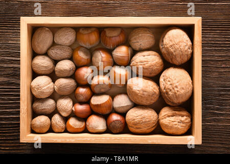 Wooden box with various nuts on table, top view Stock Photo