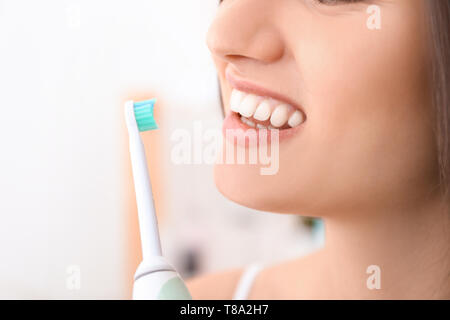 Young woman brushing her teeth in bathroom, closeup Stock Photo