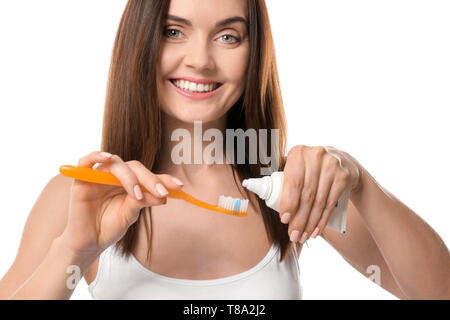 Young woman squeezing toothpaste on brush against white background Stock Photo
