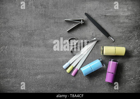 Bottles of varnish with artificial nails and tools for manicure on grey background Stock Photo