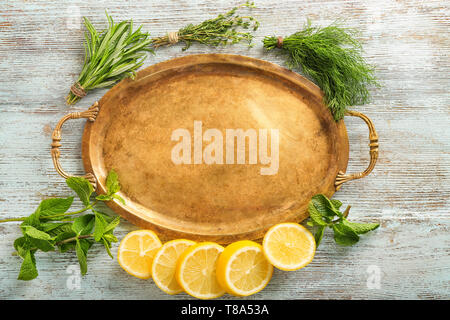 Composition with fresh herbs, sliced lemon and metal tray on wooden background Stock Photo