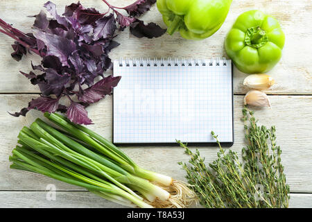 Composition with fresh herbs, vegetables and notebook on wooden background Stock Photo