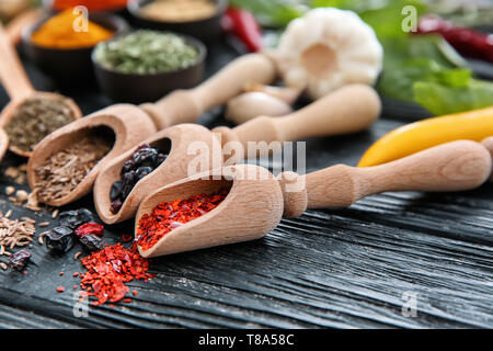 Scoops with different spices on wooden background Stock Photo