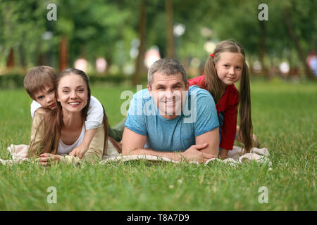 Happy family resting on plaid in park Stock Photo