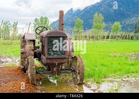 Antiquated rusty tractor on a real farm with historical engineering design of farm equipment from days old. Stock Photo