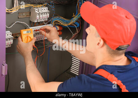 Electrician measuring voltage in distribution board Stock Photo