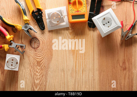Different electrician's tools and supplies on wooden background Stock Photo