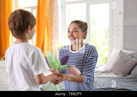 Mother receiving flowers from her cute little son at home Stock Photo