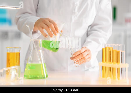 Scientist pouring color liquid into test tube in laboratory Stock Photo