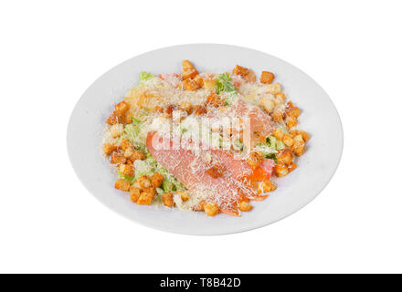 Caesar salad with three kinds of fish lobes, salmon, trout, biscuits, lettuce, cheese on plate, white isolated background, side view Stock Photo