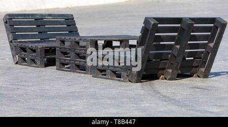 Table and chairs of pallets on the sidewalk, painted in black, the concept of street furniture Stock Photo