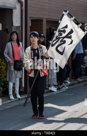 Karatsu, Japan - may 5, 2019 : young lady in traditional costumes parade through the street with a flag to celebrate new imperial era 'reiwa' Stock Photo