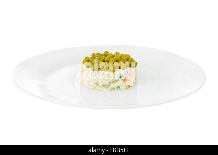 Russian salad with peas, eggs, cucumbers, carrots, ham, sausage, potatoes on plate, side view white isolated background Stock Photo
