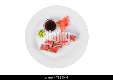 Sushi, rolls, uramaki with bacon, meat and teriyaki sauce, raw seafood, marinated ginger and wasabi, white isolated background, view from above Stock Photo