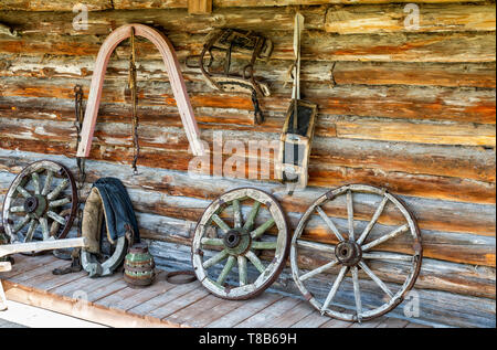 Vintage horse harnesses and wagon wheels next the barn wall in russian village Stock Photo