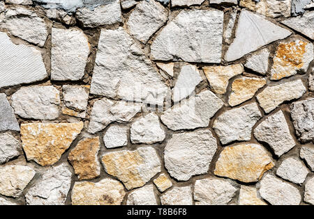 Weathered grey stone wall as creative background texture. Natural stones masonry with uneven seams. Rough stone wall texture Stock Photo