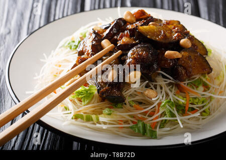 Delicious rice vermicelli with caramelized eggplants and peanuts close-up on a plate on the table. horizontal Stock Photo