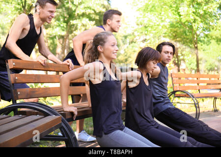 Group of young sporty people doing exercise outdoors Stock Photo