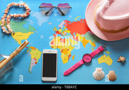 Female accessories with mobile phone on world map Stock Photo