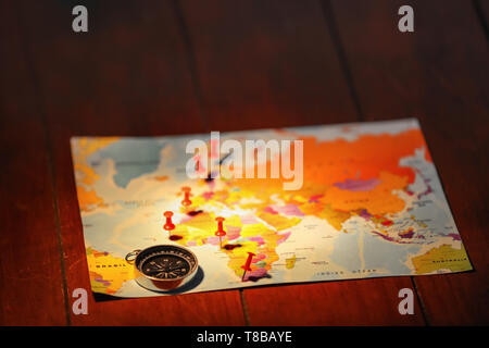 World map with compass and pushpins on table Stock Photo