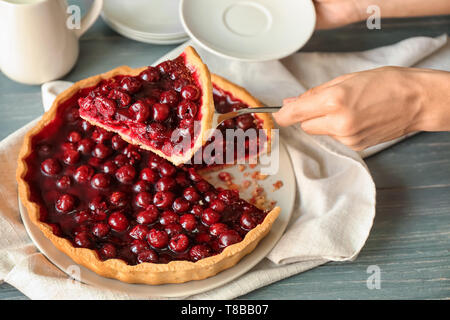 Woman taking piece of tasty homemade cherry pie from table Stock Photo