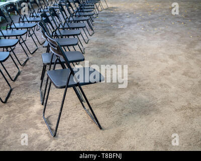 Rows of black metal folding chairs on the ground with copy space. Stock Photo
