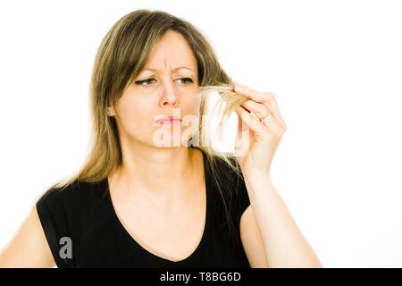 Blond woman - housewife - seeing problem with long straight hairs - frayed hair ends - white background Stock Photo