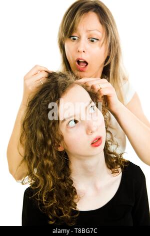 Mother checking child's head for lice showing emotion of surprise, consternation and dismay - louse on head, curly hairs - white background Stock Photo