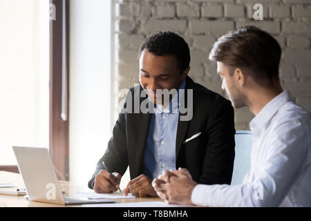 Diverse business partners after successful negotiations signing contract Stock Photo