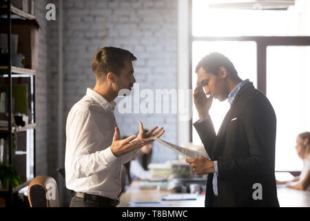 Angry director criticizing financial report accusing african man employee Stock Photo