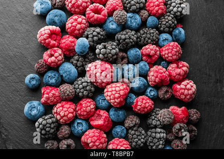 Slate plate with delicious frozen berries on dark textured background Stock Photo